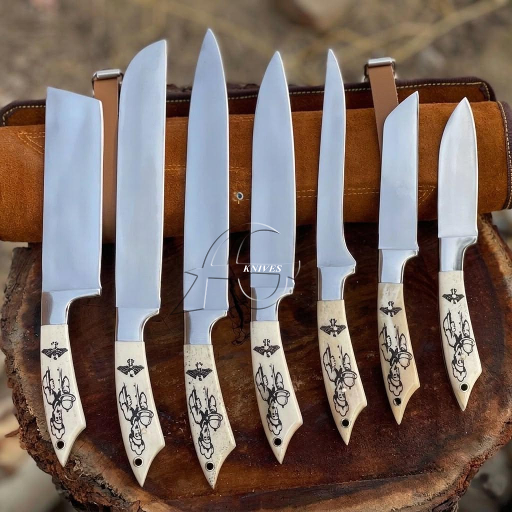 Seven fixed-blade knives with silver steel blades and cream-colored handles featuring black floral engravings, displayed upright on a rustic wooden stand.