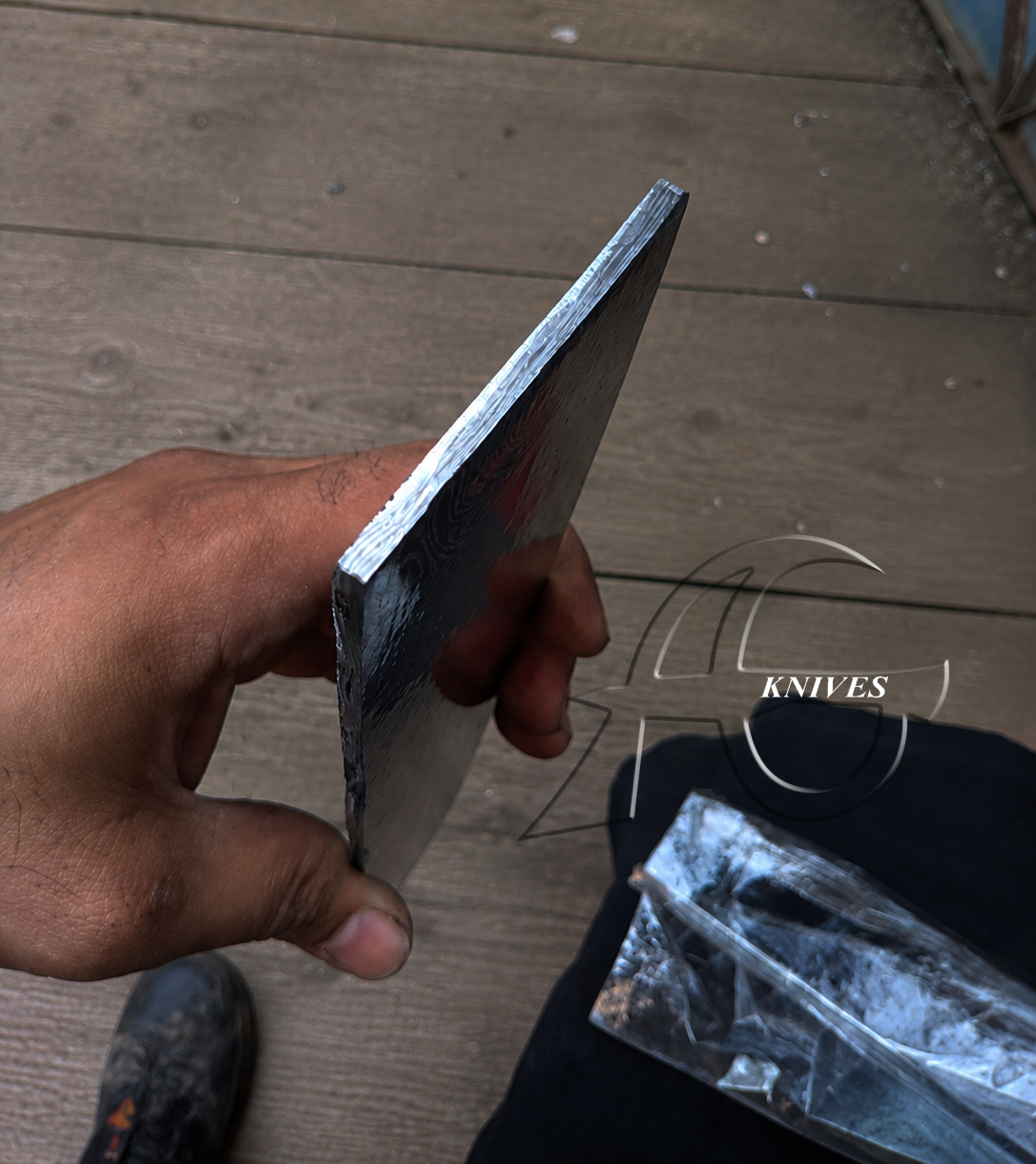 Hand holding a metal blade on a wooden floor with 'Knives' text overlay