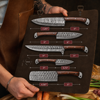 A person holds a brown leather knife storage roll displaying six different knives with labeled sizes and measurements. The knives have hammered steel blades and brown wood handles.
