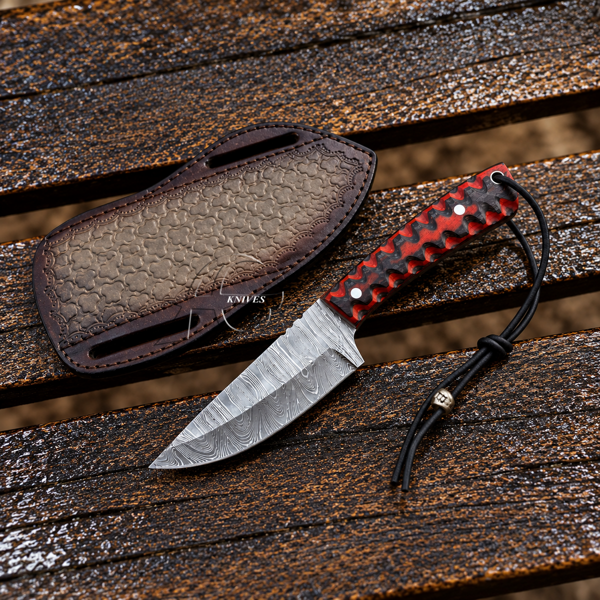 A fixed-blade knife with a patterned steel blade, red and black handle scales, and a black cord lanyard, shown beside a matching textured brown sheath on a weathered wooden surface. The brand name 'NANOS' is visible on the sheath.