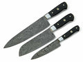 Three kitchen knives with patterned Damascus steel blades and black handles, arranged diagonally on a plain white background.