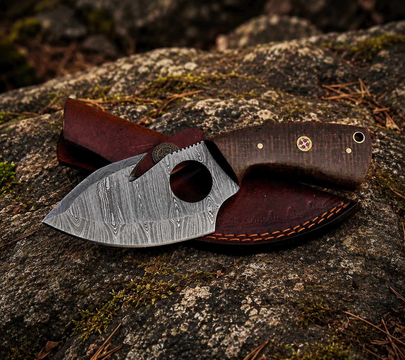A fixed-blade knife with a patterned steel blade and dark brown handle, resting on a dark brown leather sheath on a mossy rock outdoors.