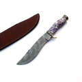 A custom fixed-blade knife with a patterned Damascus steel blade, a purple and white marbled handle, and a brass guard, shown next to its brown leather sheath on a white background.