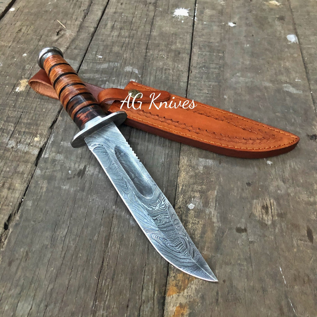Decorative knife with a leather sheath on a wooden surface, branded 'AG Knives'.
