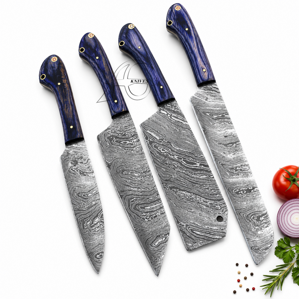 Four kitchen knives with patterned Damascus steel blades and dark blue wooden handles, arranged diagonally on a white background with food props like a tomato, onion, and herbs.