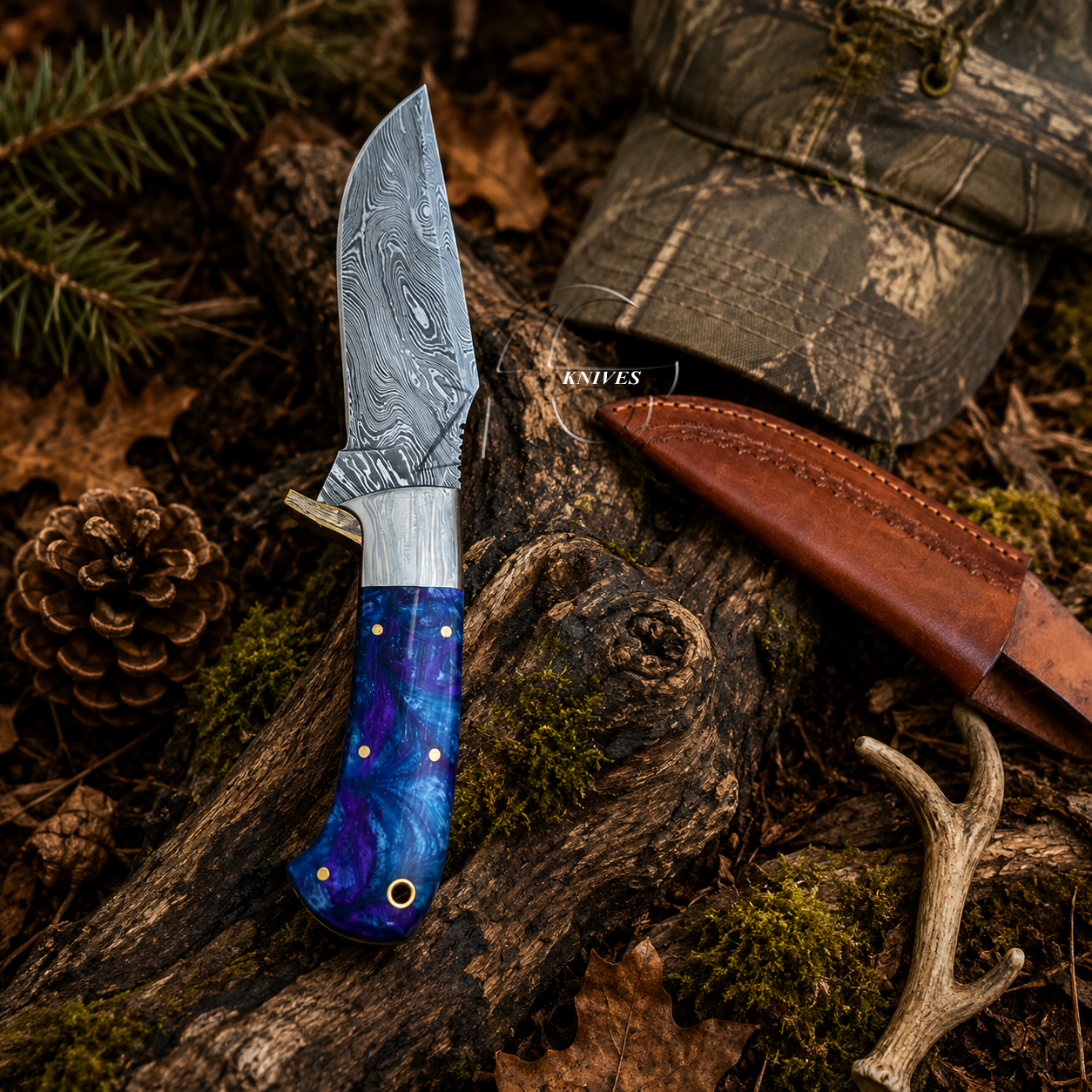 A fixed-blade knife with a patterned steel blade and a blue-purple handle lies on a log outdoors, with a brown leather sheath and a camouflage cap nearby in a forest setting.