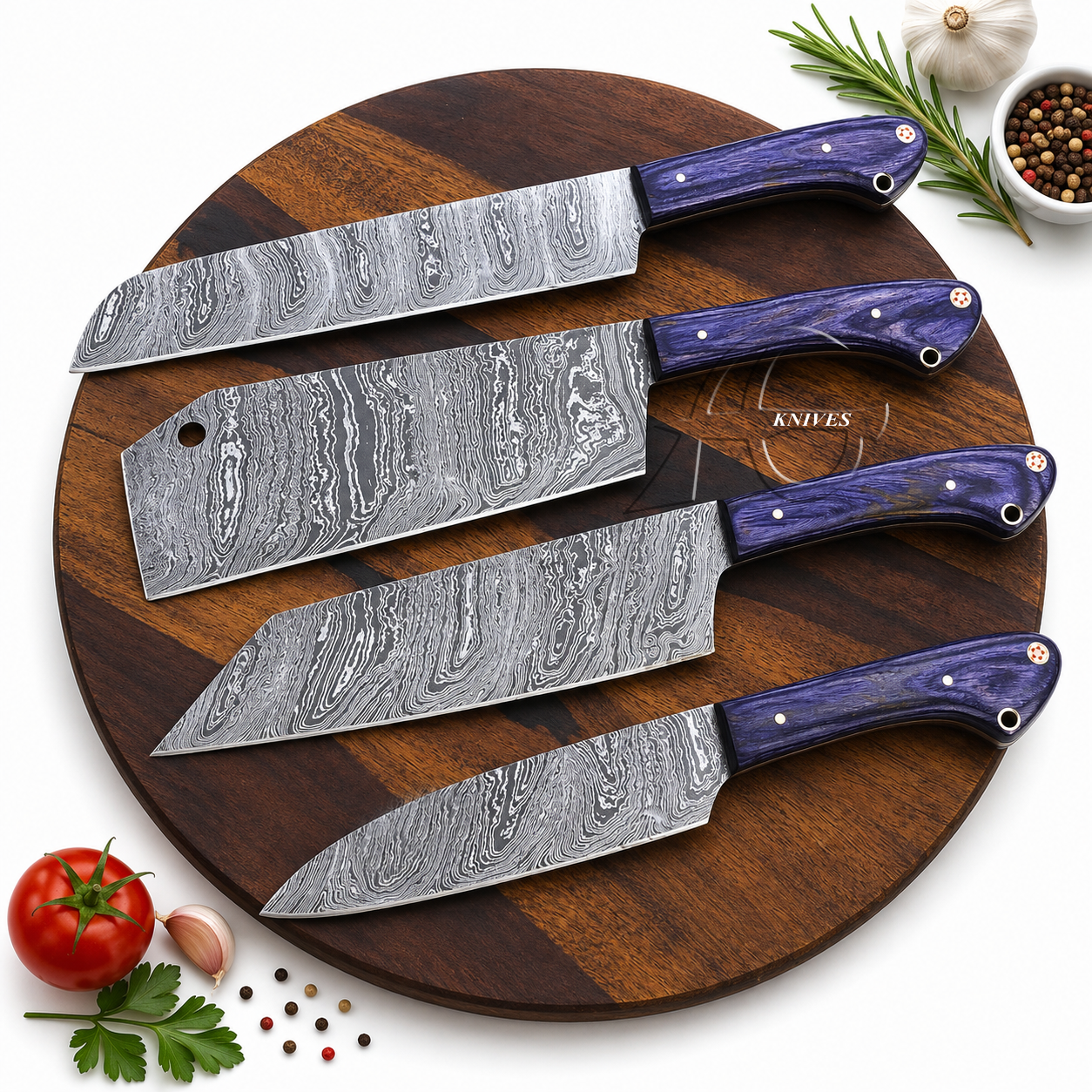 Four kitchen knives with patterned Damascus steel blades and purple handles arranged on a round wooden cutting board, with small food props including a tomato, garlic, parsley, peppercorns, and rosemary around the board.
