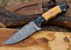 A fixed-blade knife with a patterned Damascus steel blade, a black and wood handle, and a brown leather sheath, displayed on a rustic wood surface.