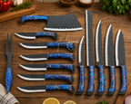 A 12-piece kitchen knife set arranged on a rustic wooden table, featuring textured dark gray blades and vibrant blue marbled handles with orange and white speckles. The set includes a cleaver, knives, a carving fork, and a sharpening steel, with kitchen props like lemon slices, parsley, and a cutting board in the background.