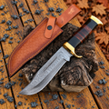 A custom Damascus steel fixed-blade knife with a dark wood handle and gold guard, displayed diagonally on a rustic wood log with its brown leather sheath.
