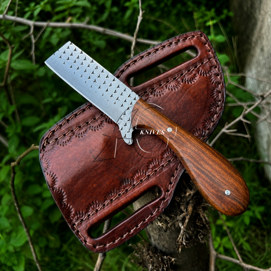 A fixed-blade knife with a file rasp steel silver blade and a brown wooden handle, resting on its brown leather sheath outdoors against a background of green foliage and branches.